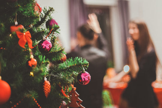 People at a Christmas party reception with a Christmas tree in the foreground