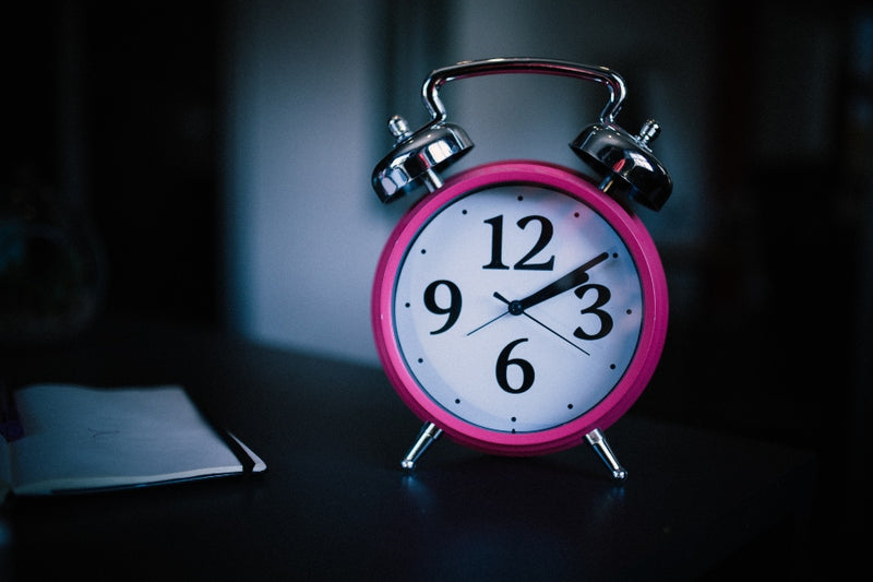 Pink alarm clock to illustrate overnight skin care tips 