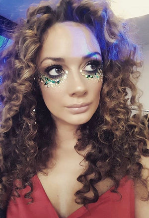 woman with curly hair wearing green and blue glitter